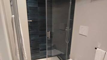 Een moderne badkamer met een douchecabine van glas, een toilet en een wastafel.