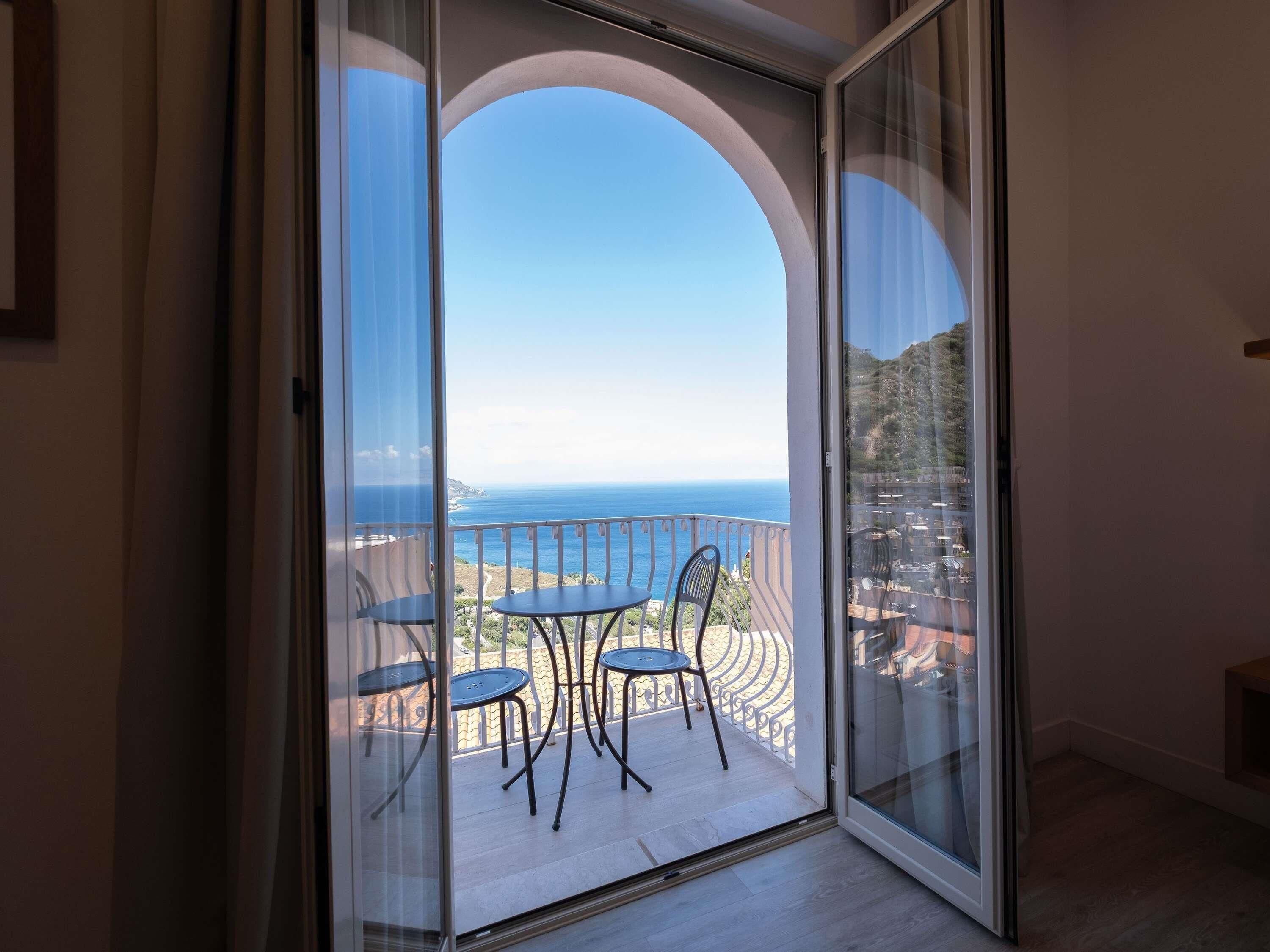 A balcony with a clear view of the sea and a mountainous landscape.