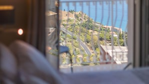 Quarto com vista para a paisagem costeira, incluindo uma estrada e edifícios.