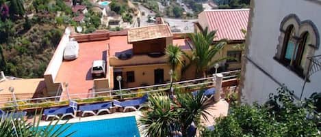 Un quartier résidentiel doté d’une piscine, entouré d’une végétation luxuriante et offrant une vue sur la côte.