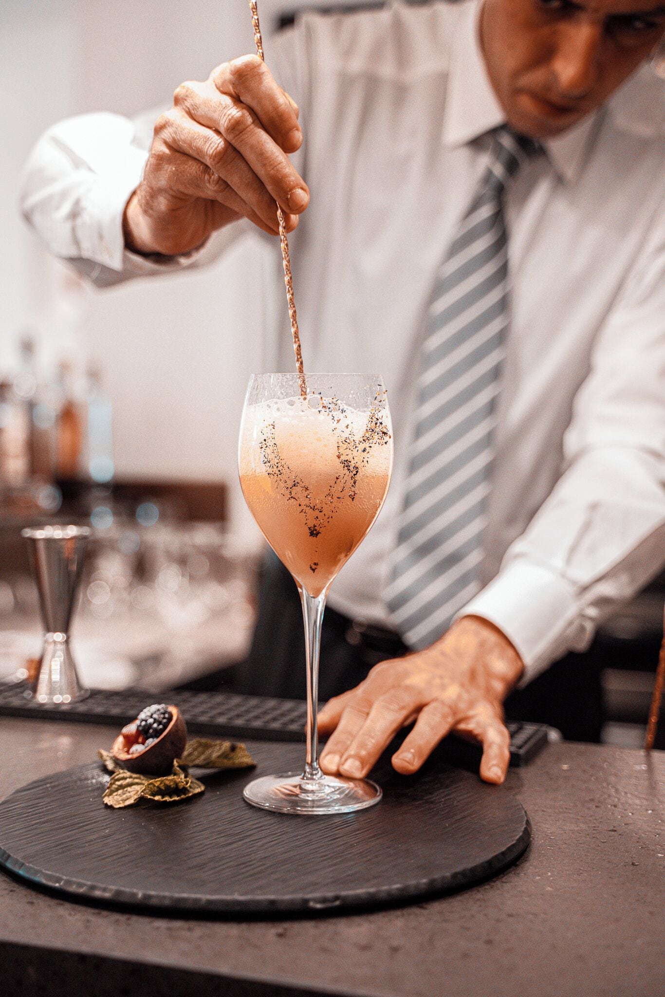 A bartender pouring a drink into a glass.