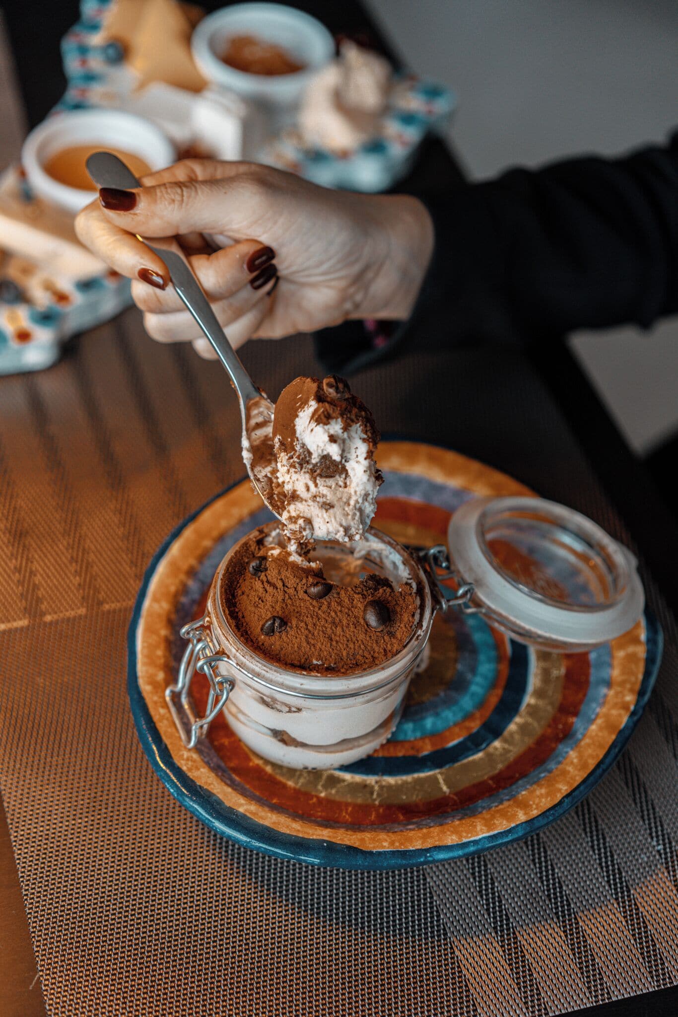 Un dessert in un vasetto di vetro, con un cucchiaino che lo solleva.