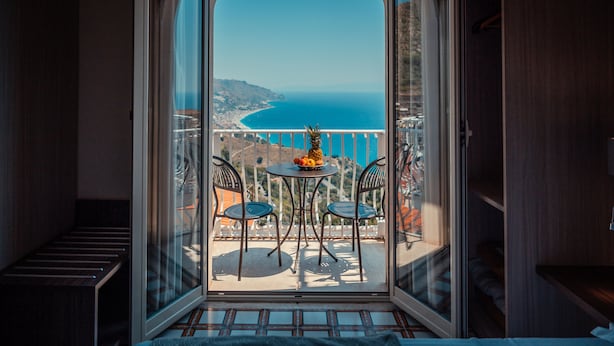 Varanda com mesa e cadeiras, vista para o litoral.