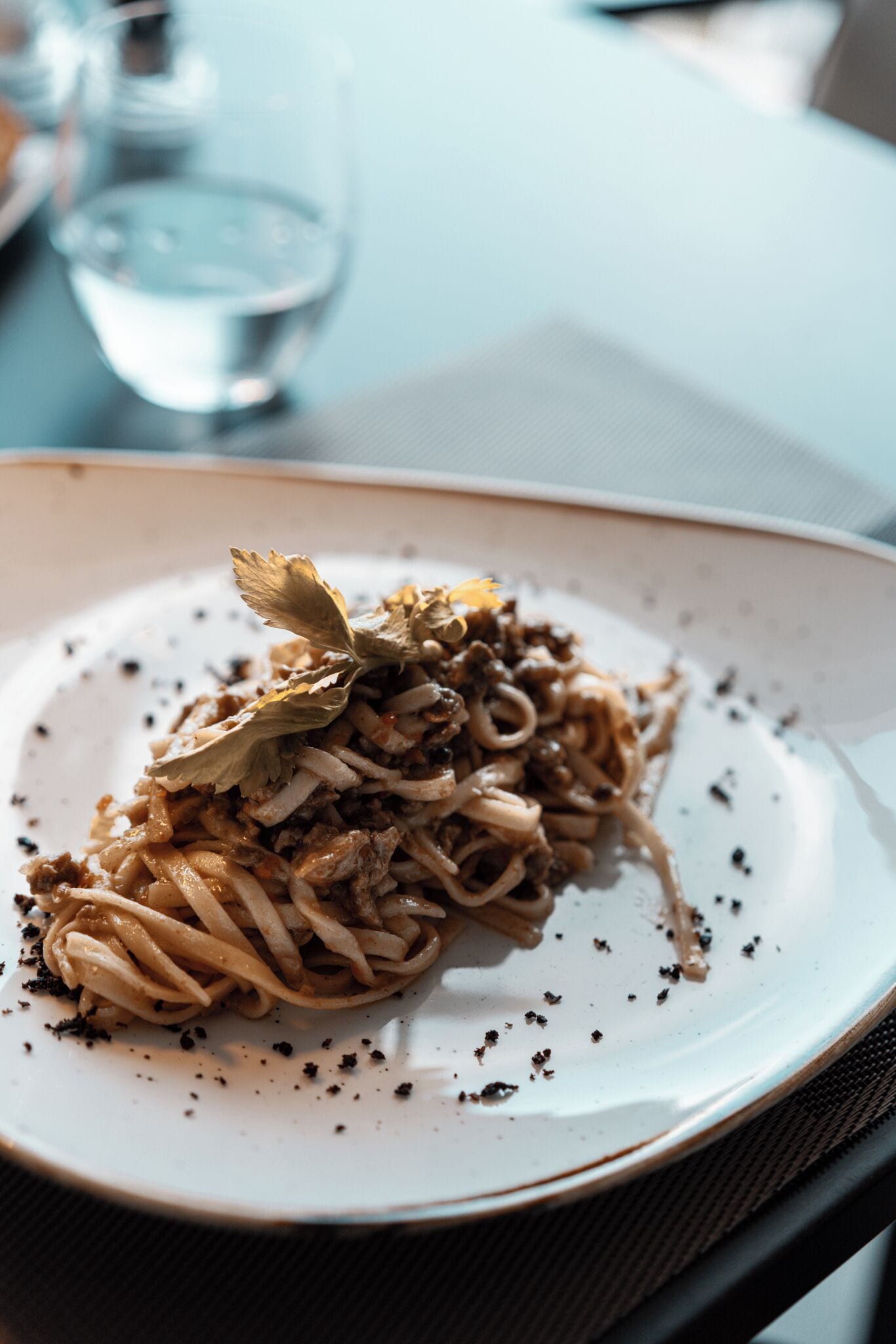 A plate of spaghetti with a garnish on a white plate.