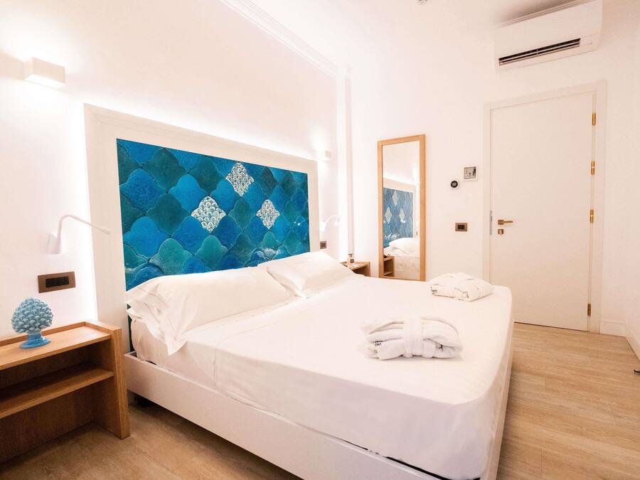A hotel room with a bed, a nightstand, a mirror, and a wall with a geometric pattern.