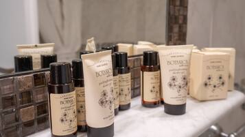 A bathroom with a marble countertop displaying various botanical shower gels and body washes.