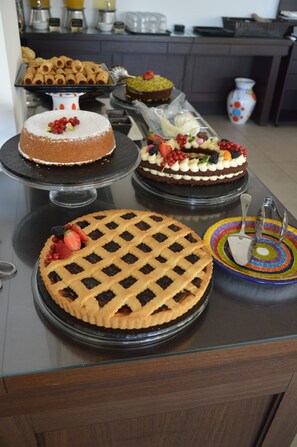 Una presentación de postres con diversos pasteles y tartas sobre una mesa de vidrio.