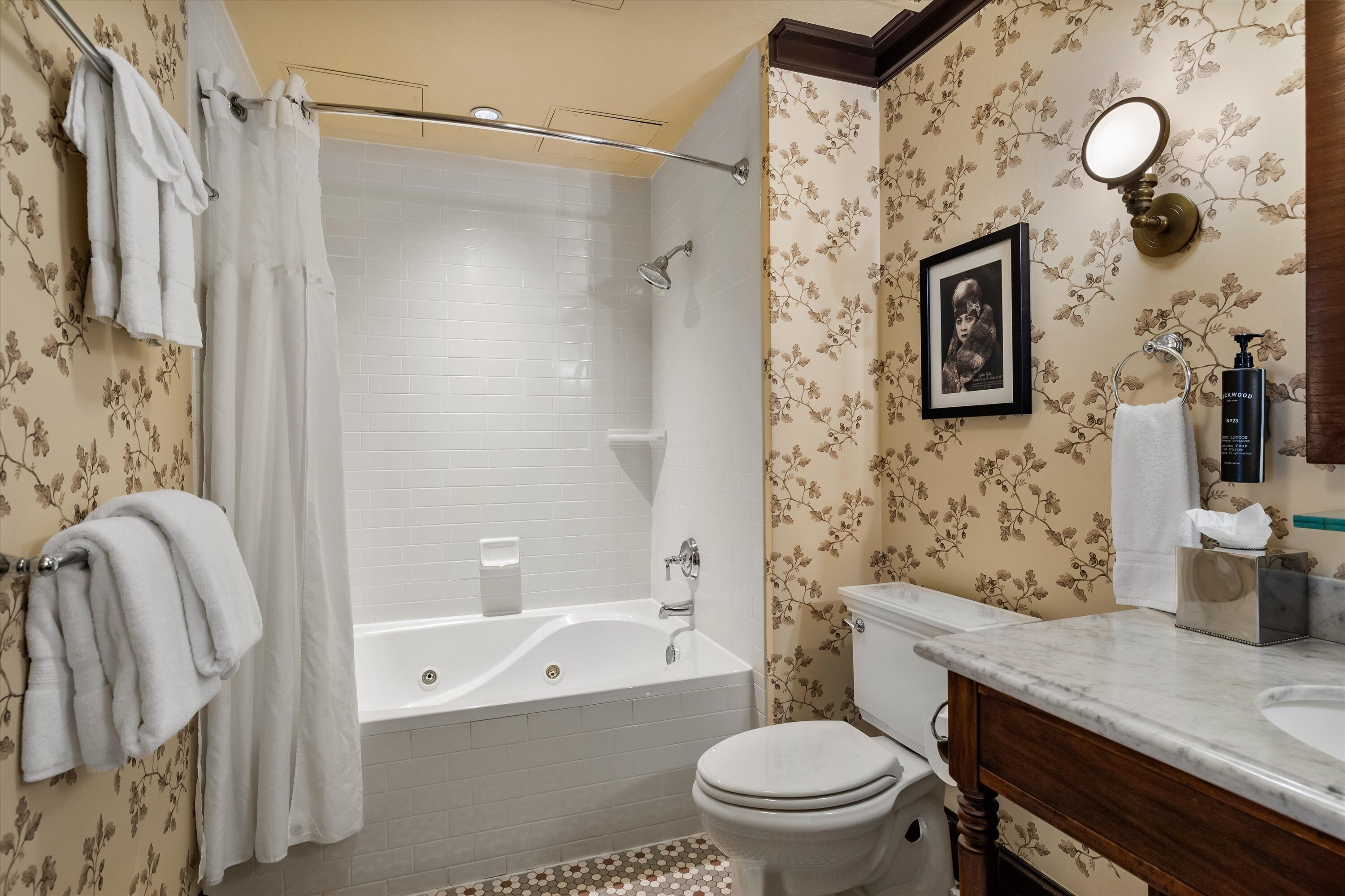 A bathroom with a bathtub, toilet, and a vanity with a mirror.