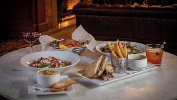 A dining table with various dishes including a salad, soup, sandwiches, fries, and a drink.