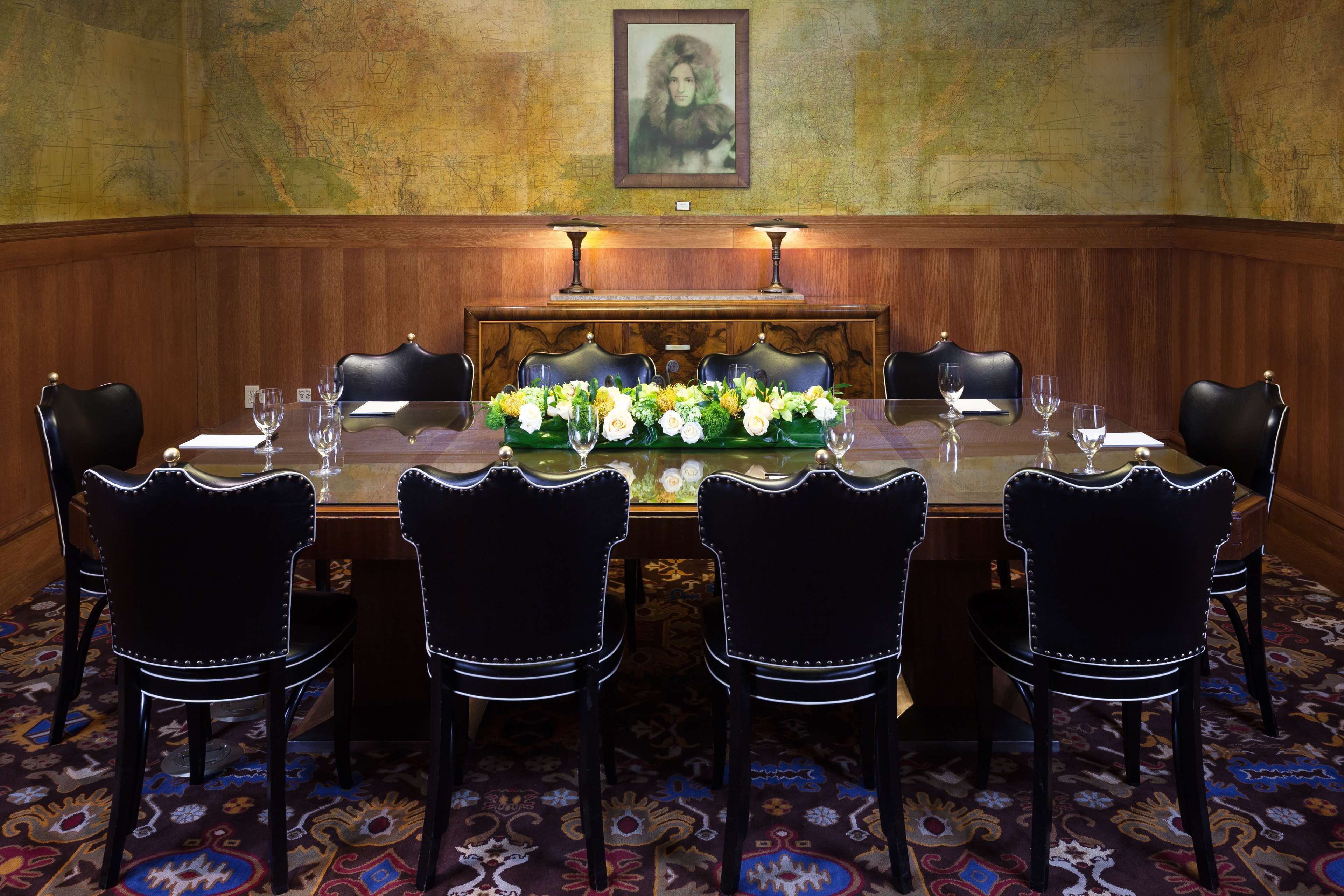 A conference room with a long table, six chairs, and a floral centerpiece.