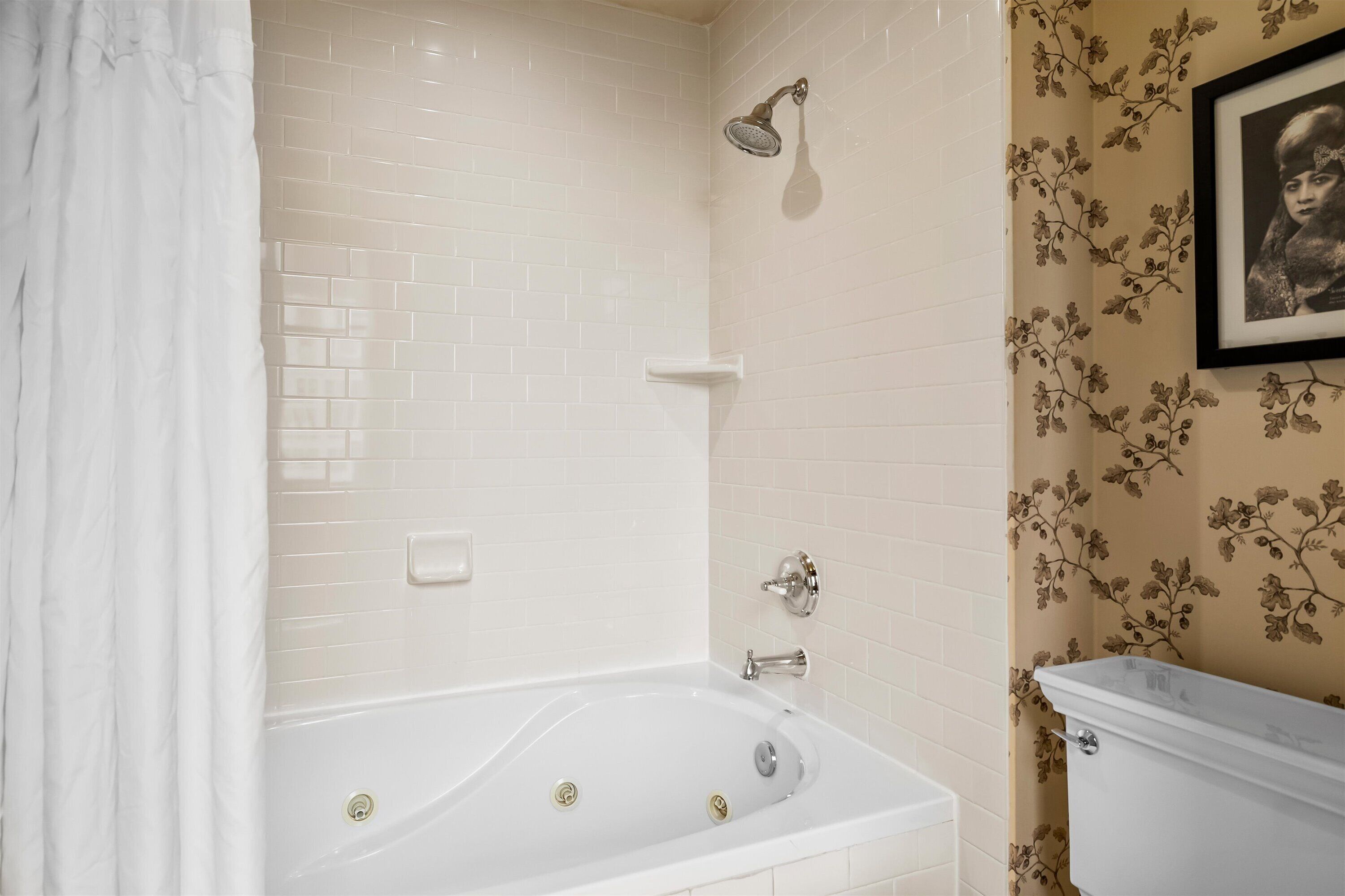 Un baño con una bañera blanca, ducha e inodoro.