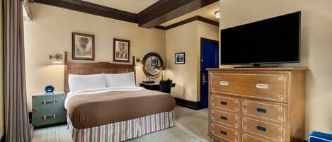 Una habitación de hotel con cama, cómoda, televisor y maleta.