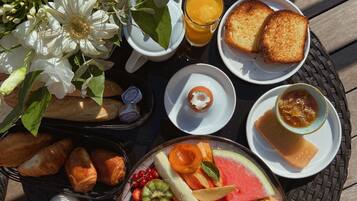 Une table garnie de divers aliments, notamment du pain, des fruits et une boisson.