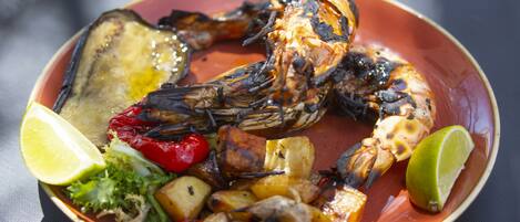 A plate of grilled seafood with vegetables and lime wedges.