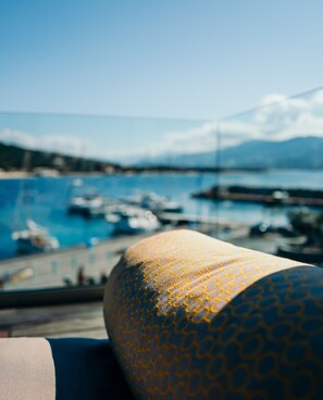 A view from a window overlooking a marina with boats, a clear sky, and distant mountains. - Hôtel Le Golfe (Serra-di-Ferro)