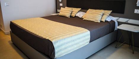 A modern hotel room with a large bed, a bedside table, and a nightstand.