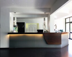 Un mostrador de recepción moderno con un logotipo, una vitrina de cristal y una encimera de madera.