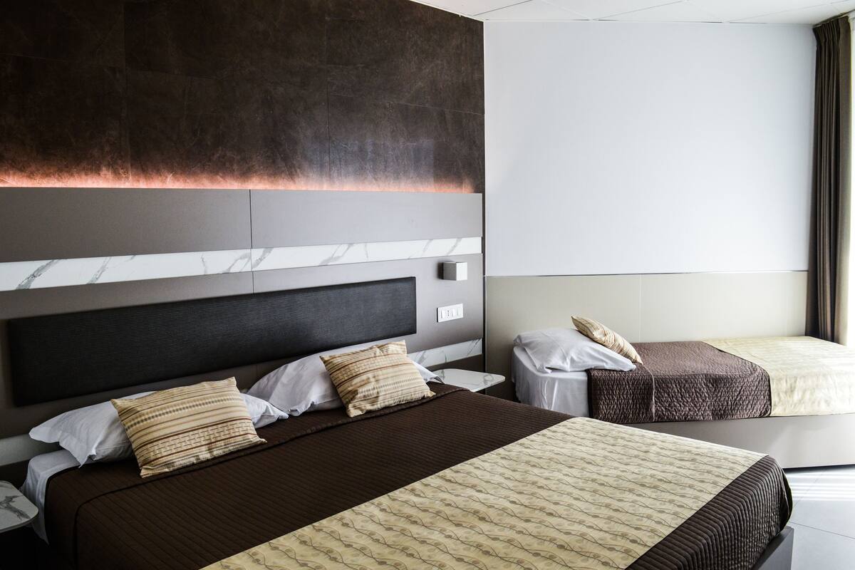 A hotel room with a large bed, a smaller bed, and a nightstand.