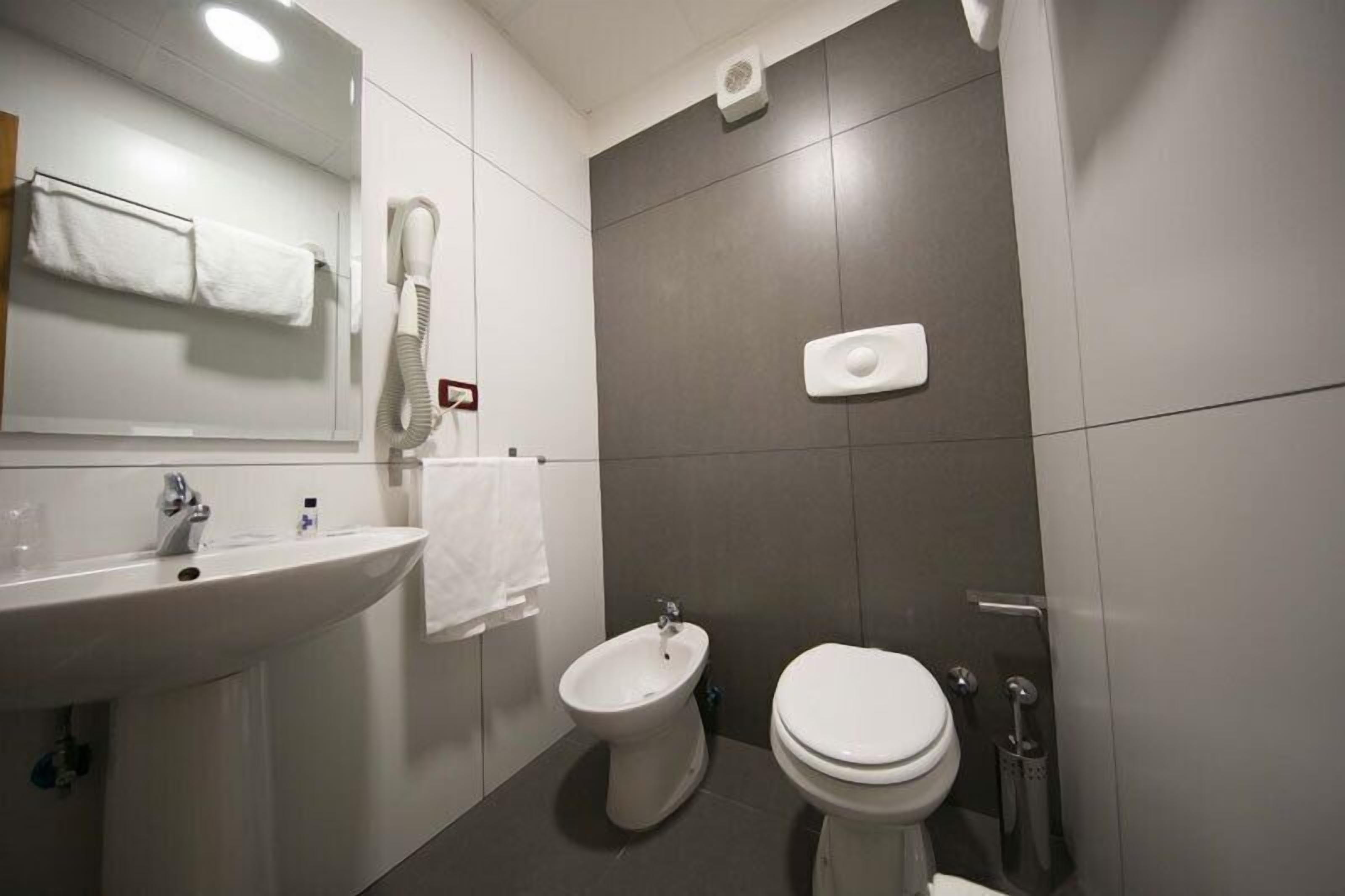 A modern bathroom with a sink, bidet, and toilet.