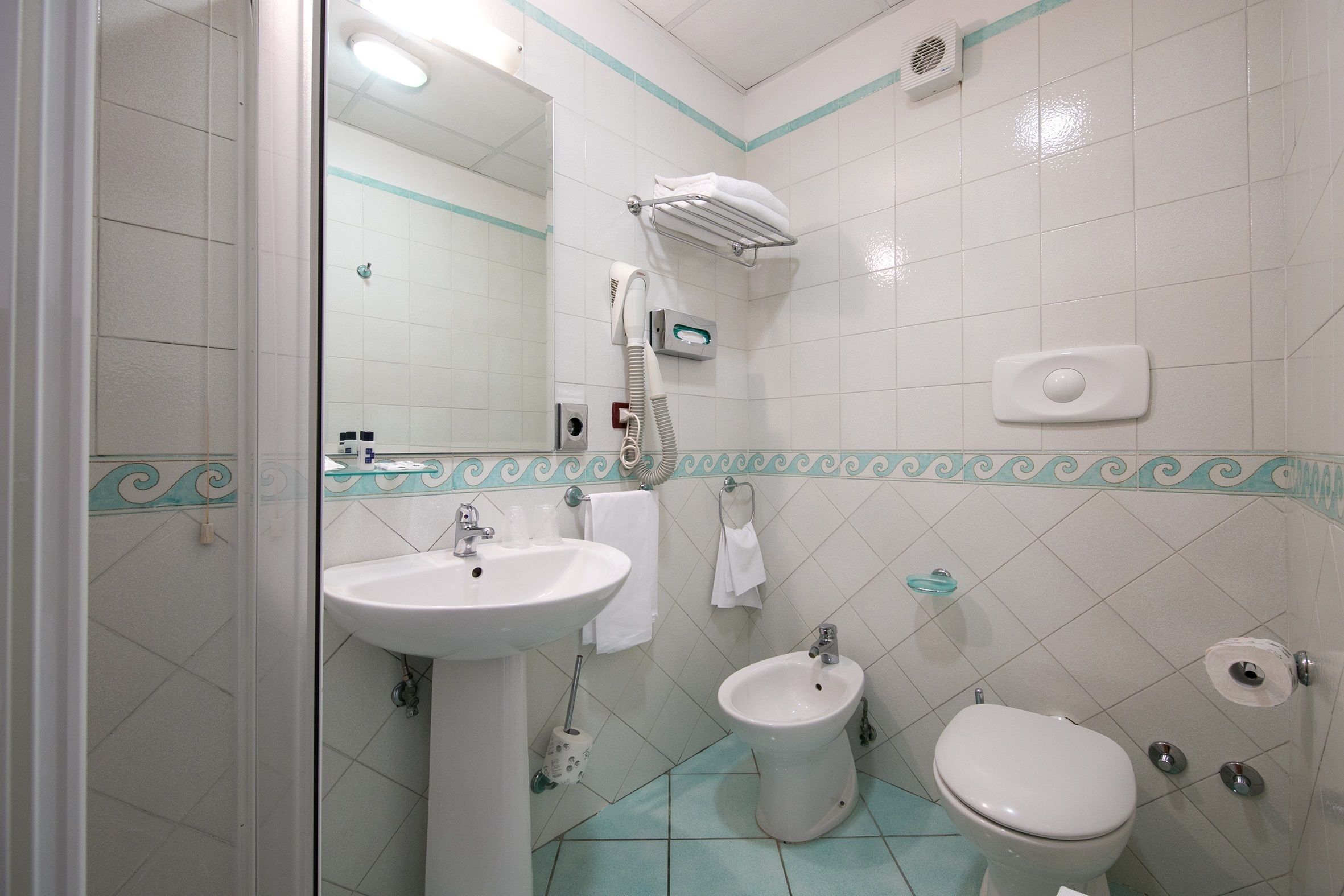 Une salle de bain équipée d’un lavabo, d’un bidet, de toilettes et d’un porte-serviettes.