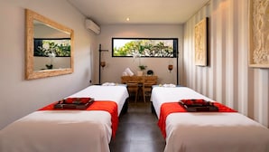 A hotel room with two beds, a desk, and a window with a view of greenery. - Bali Island Villas and Spa Seminyak (Seminyak)