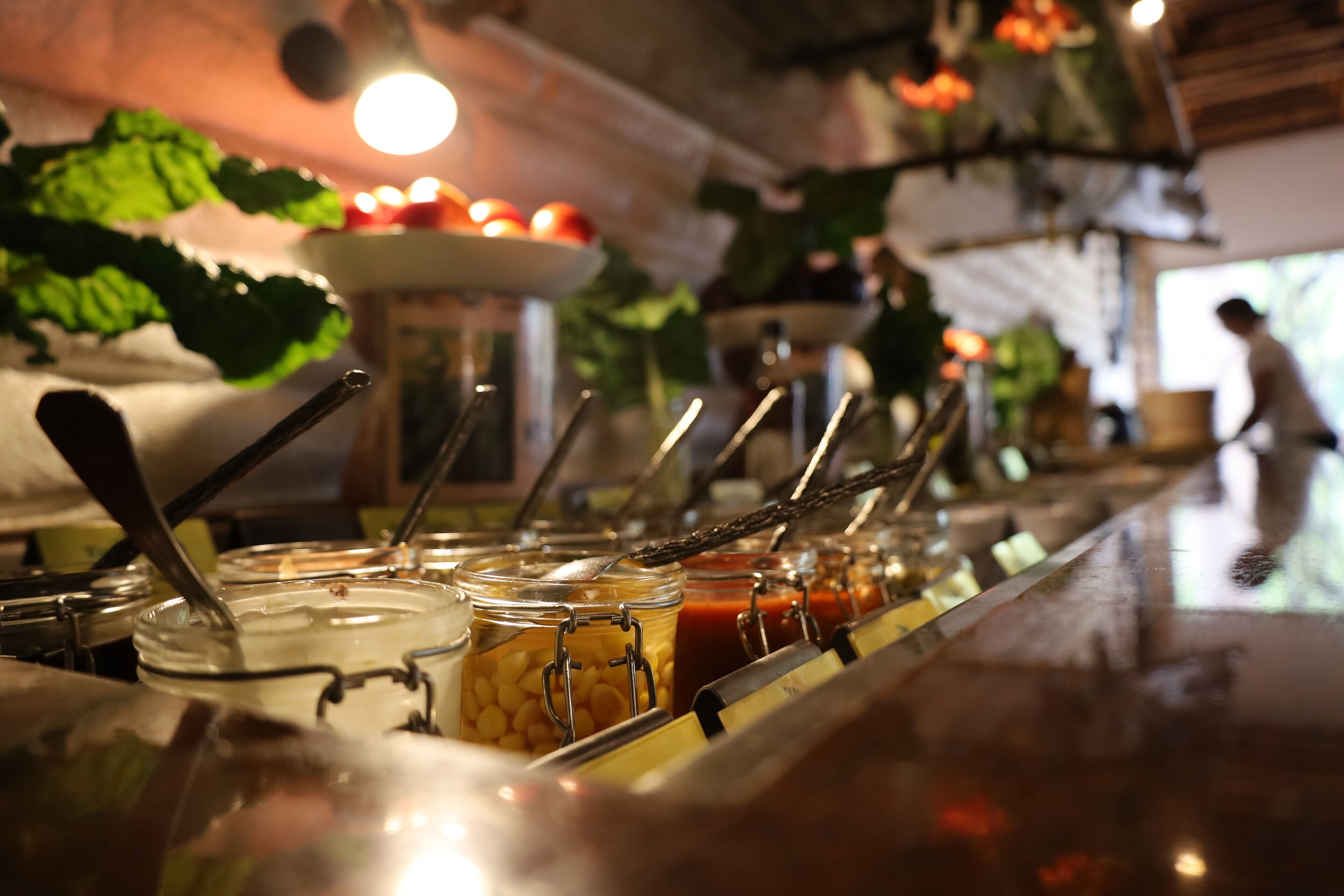 Un buffet avec différents plats présentés dans des récipients variés et accompagné d’ustensiles.
