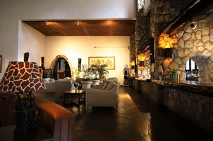 Un área de descanso acogedora con pared de piedra, chimenea y bar. Hay sofás y una mesa de centro.