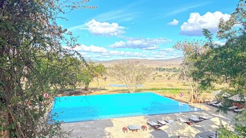Una piscina con sillas de descanso y vistas a un paisaje natural.