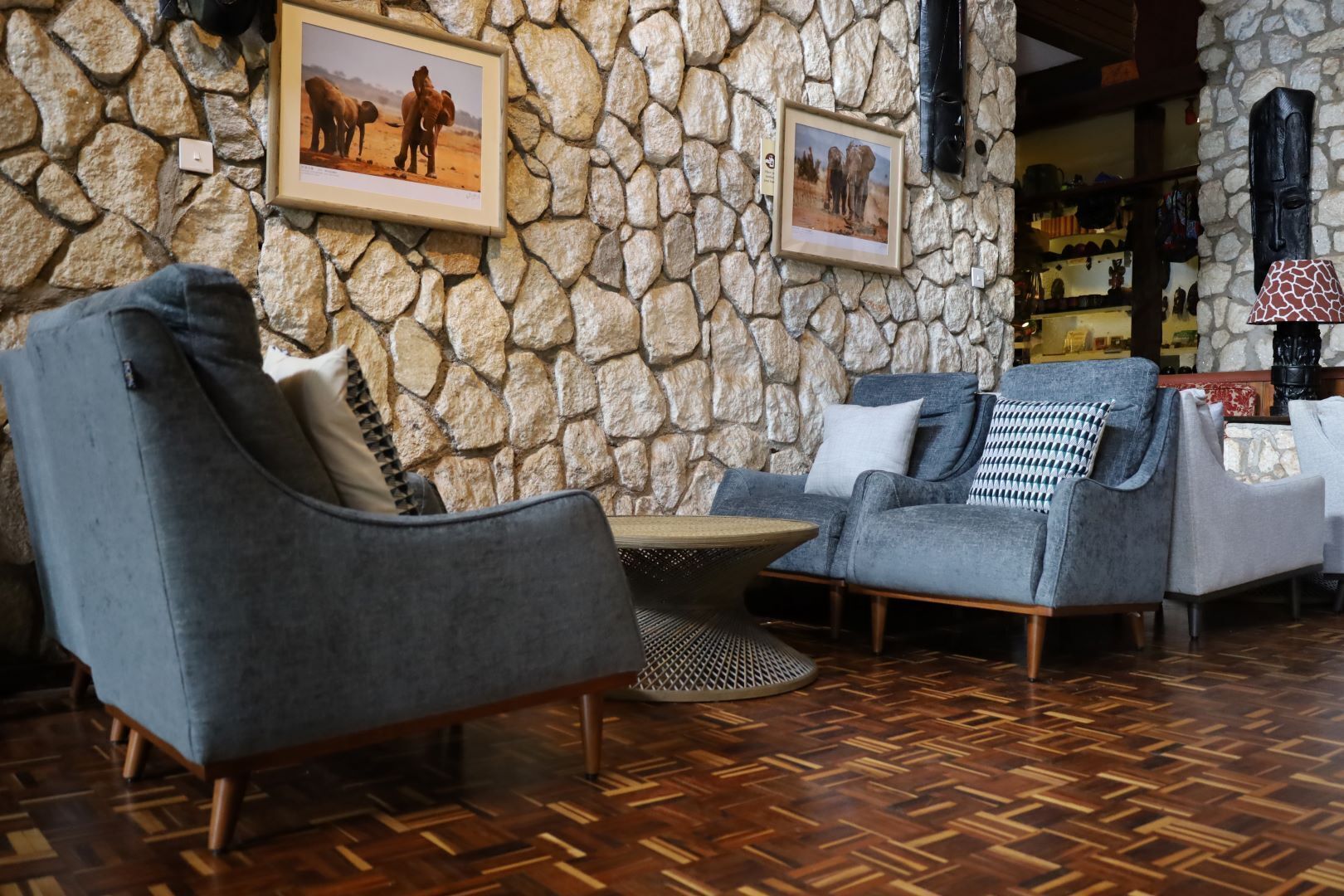 A stone-walled lounge area with two grey armchairs and a small round table.