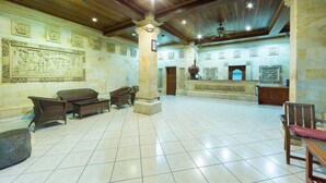 Un hall espacioso con techos altos, pisos de baldosas y detalles arquitectónicos clásicos, incluyendo columnas y relieves en las paredes.