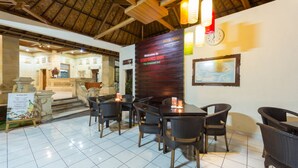 Un restaurante con piso de baldosas, mobiliario de mimbre, techo de madera y un letrero de bienvenida para Simpang Inn.