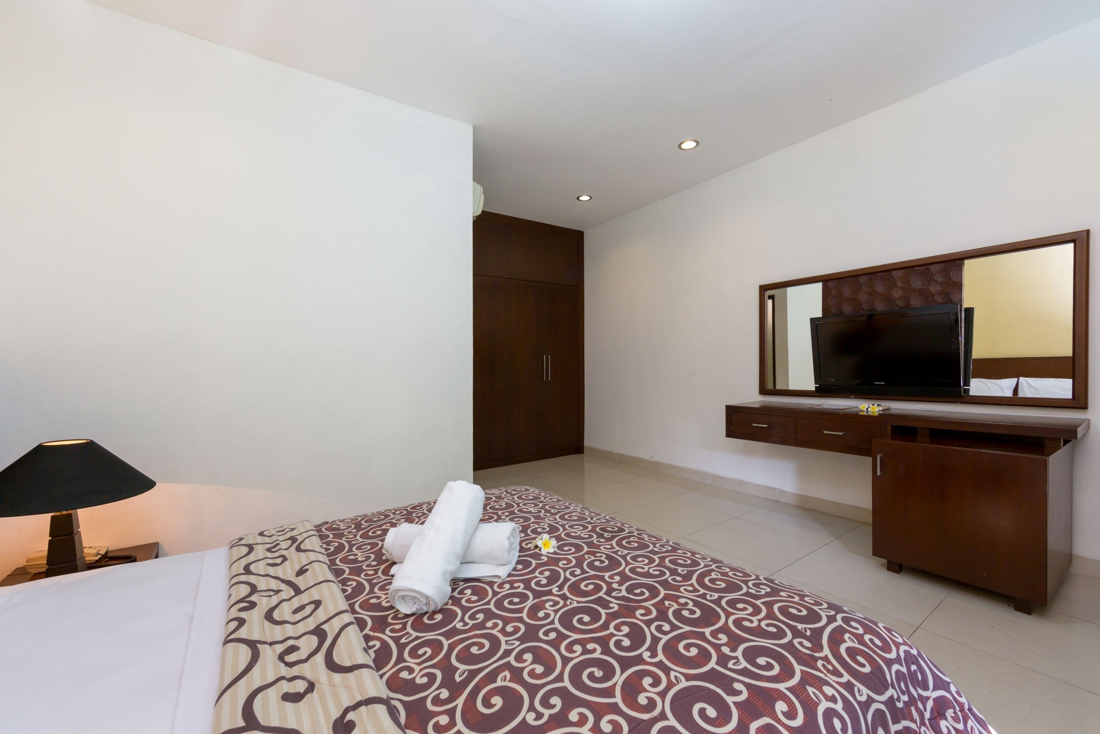 A hotel room with a bed, a desk, a television, and a wardrobe.