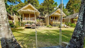 A resort with wooden cabins, a grassy yard, and a rope swing.