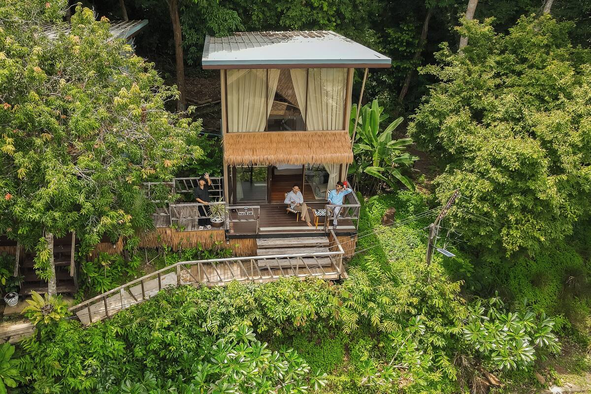 Une construction en bois, surmontée d’un toit de chaume, entourée d’une végétation luxuriante.