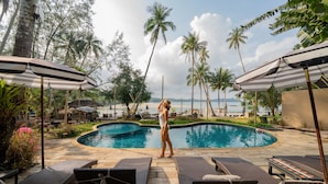 A poolside area with lounge chairs, umbrellas, and a view of the ocean.