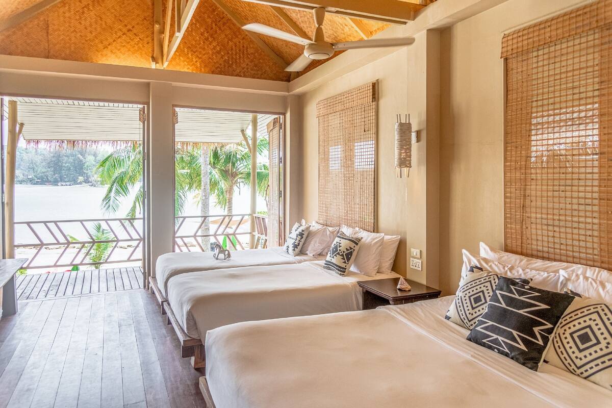 Une chambre d’hôtel avec deux lits, un ventilateur de plafond et vue sur la plage.