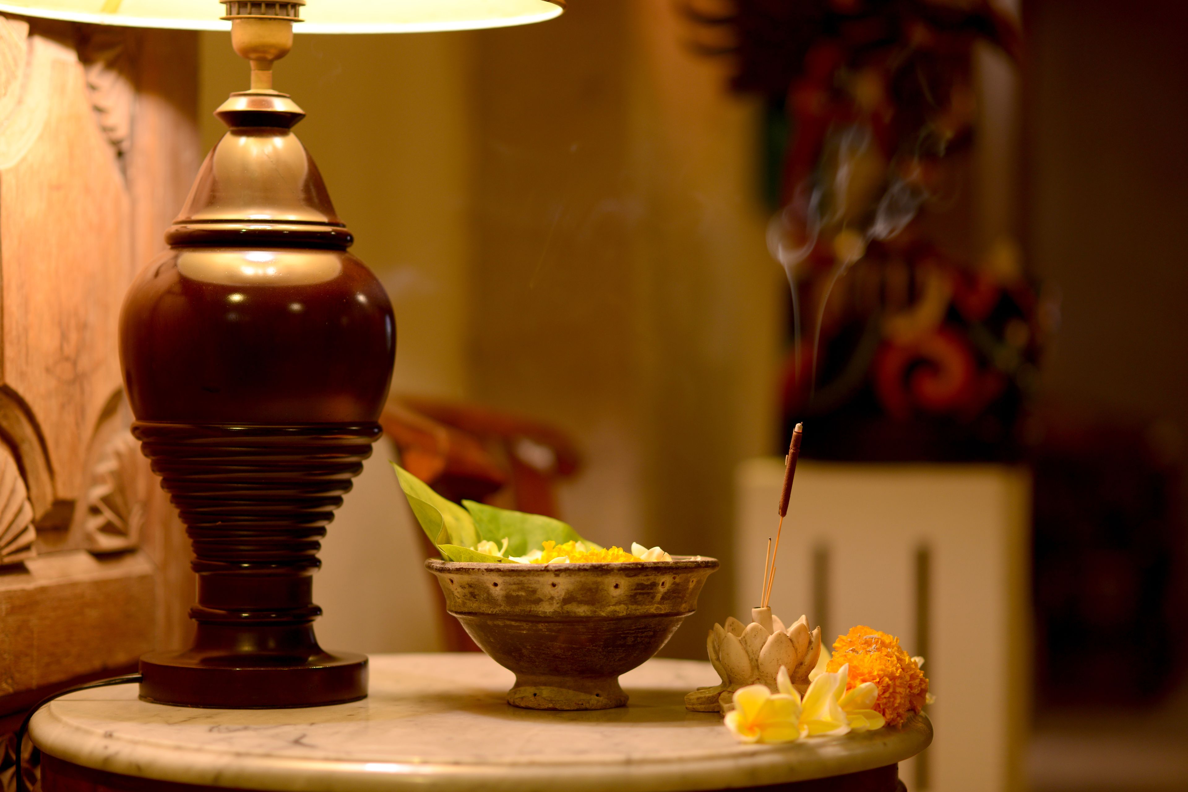 A table with a lamp, a bowl of flowers, and a decorative item.