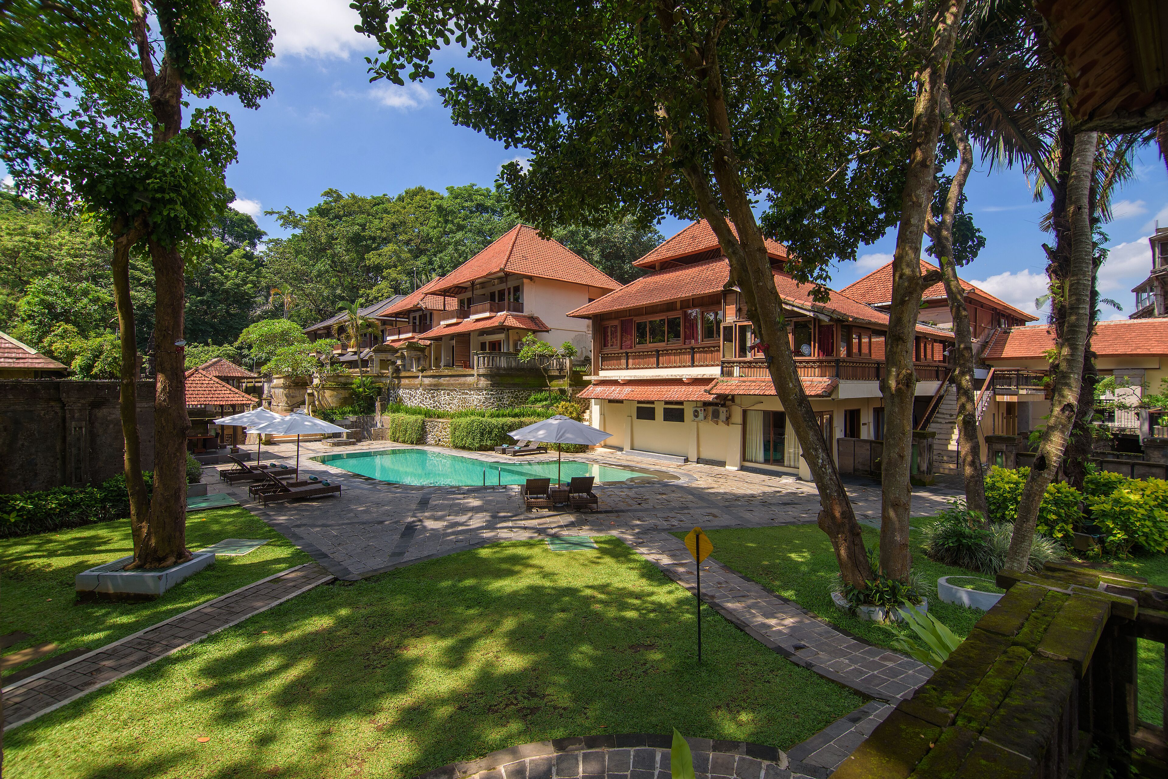 A pool area with lounge chairs and umbrellas, surrounded by traditional-style buildings with red roofs and balconies.