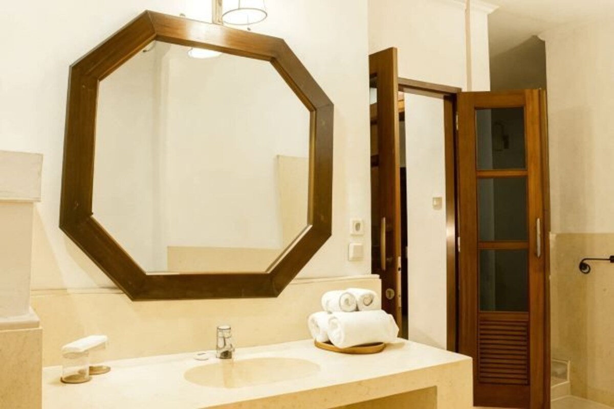 Un baño con un espejo octagonal grande, un lavabo y una zona de ducha.