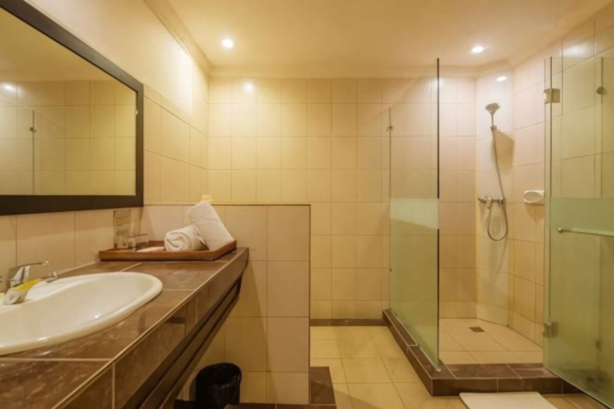 Een badkamer met een wastafel, spiegel, douche en betegelde wanden.