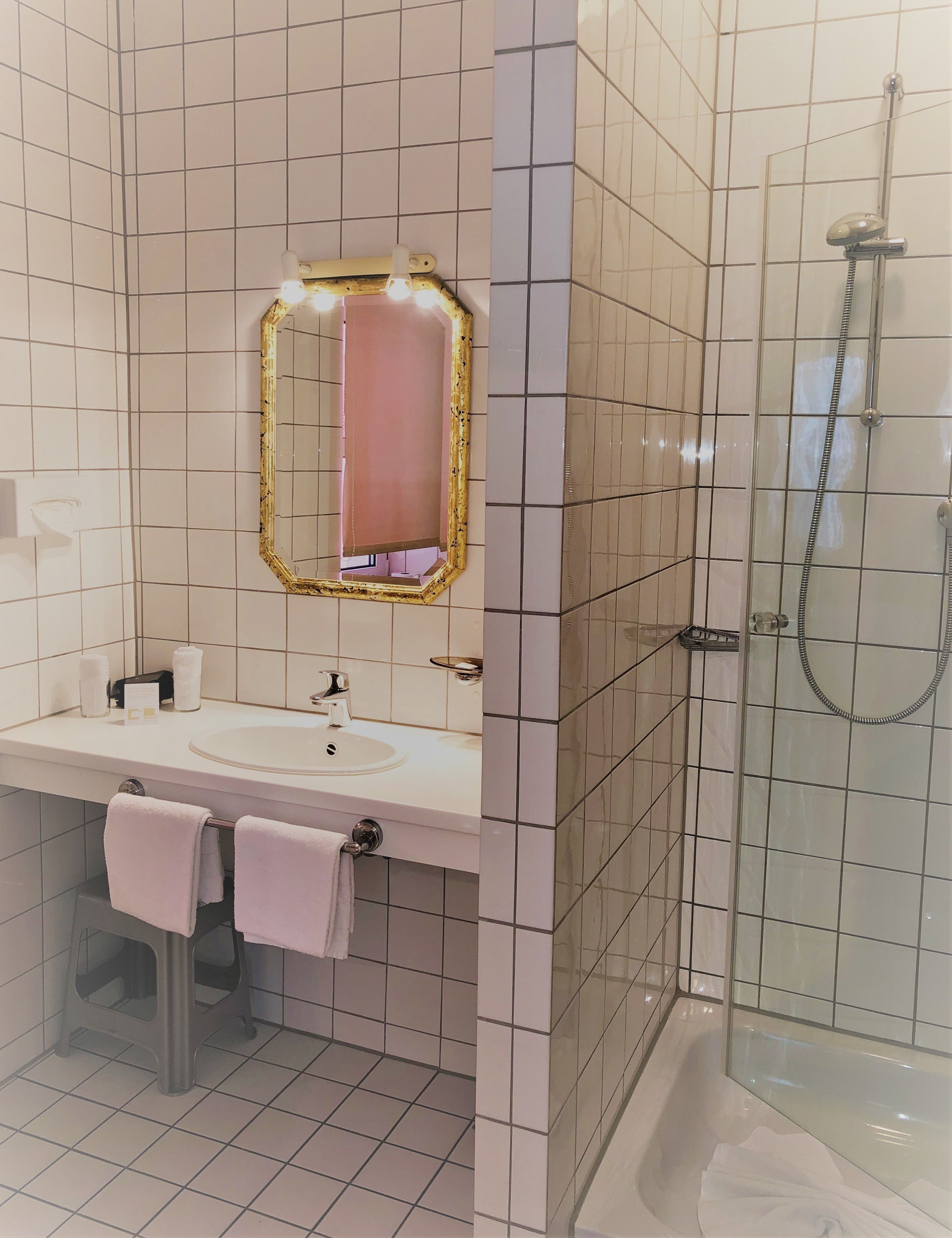 A bathroom with a sink, mirror, and shower.