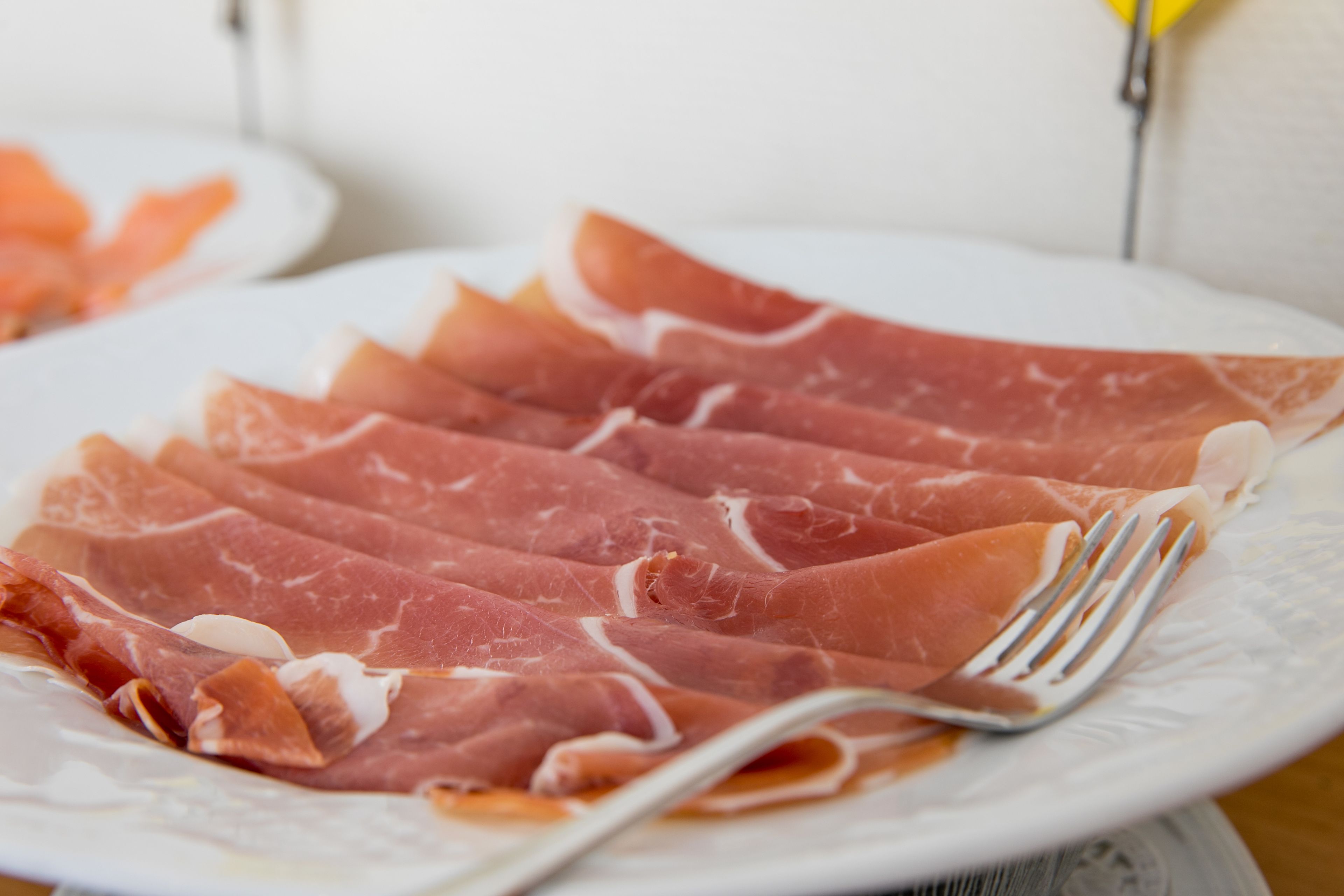 A plate of sliced cured meat with a fork.