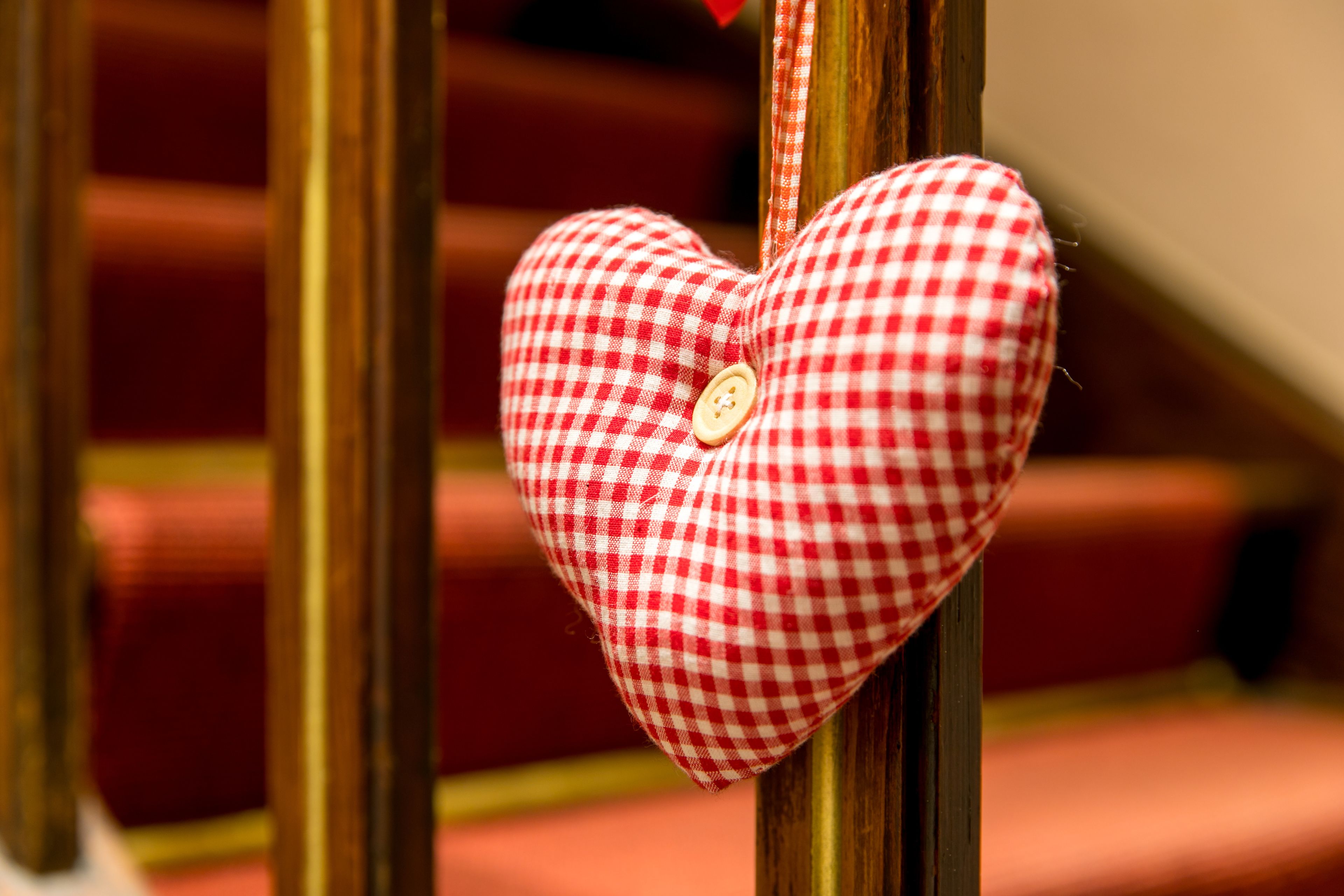 Adorno con forma de corazón y un botón, colgado de una barandilla de madera.