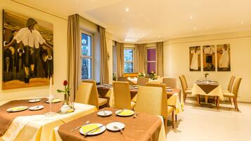 A dining area with tables set for four, featuring brown tablecloths and yellow napkins.