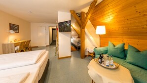 A hotel room with a bed, a sofa, a dining area, and a staircase. - CityHotel Kempten (Kempten)