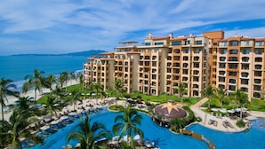 Un resort con una piscina grande, varios balcones y vista al océano.