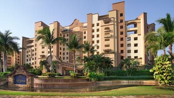 A multi-story hotel with a central courtyard, palm trees, and a fountain.