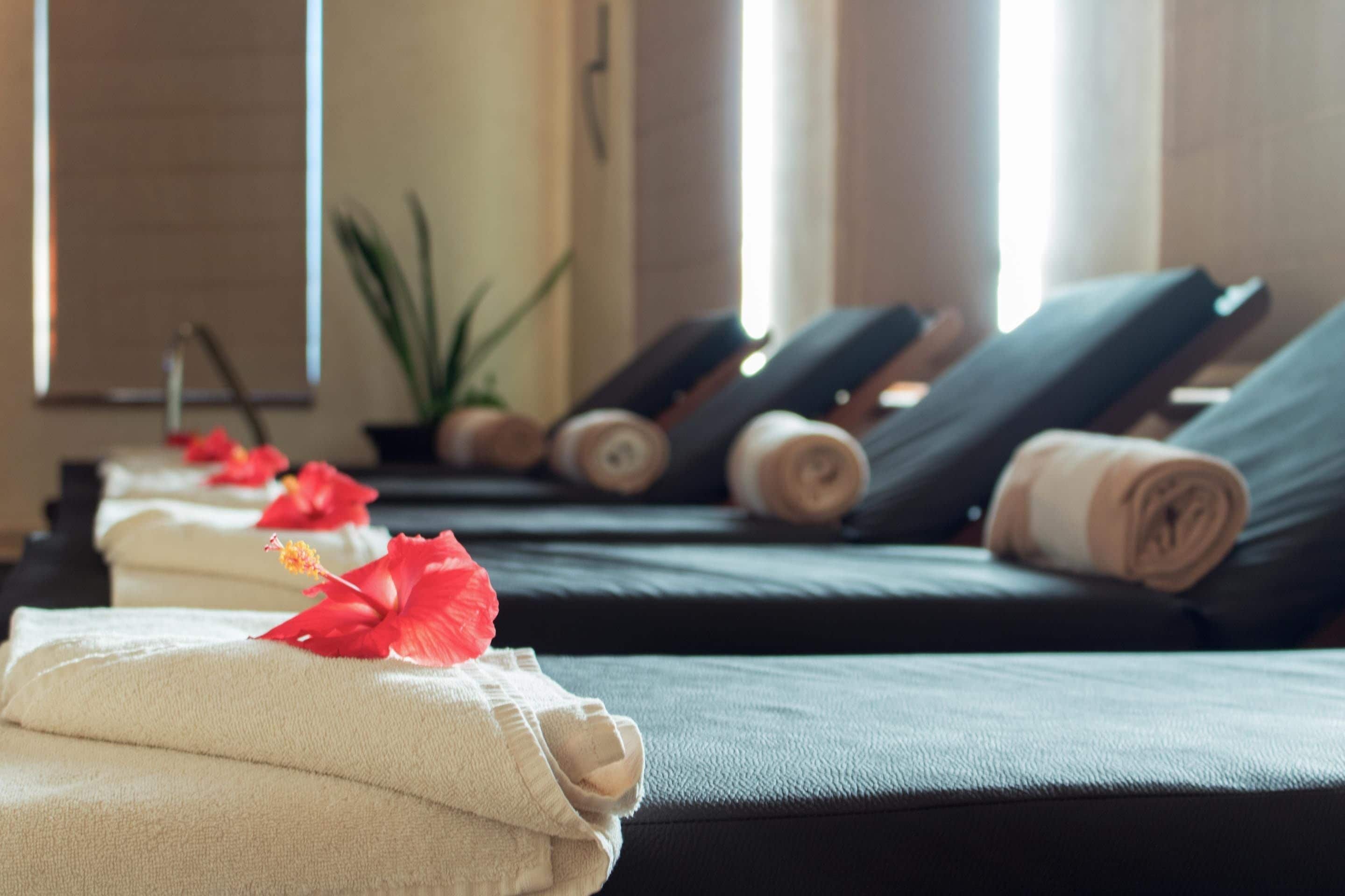 A spa room with massage tables, towels, and decorative flowers.