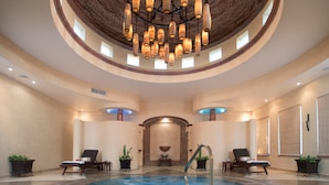 A large indoor pool with a central fountain, surrounded by lounge chairs and potted plants. - Villa La Estancia Beach Resort & Spa Riviera Nayarit (Nuevo Nayarit)
