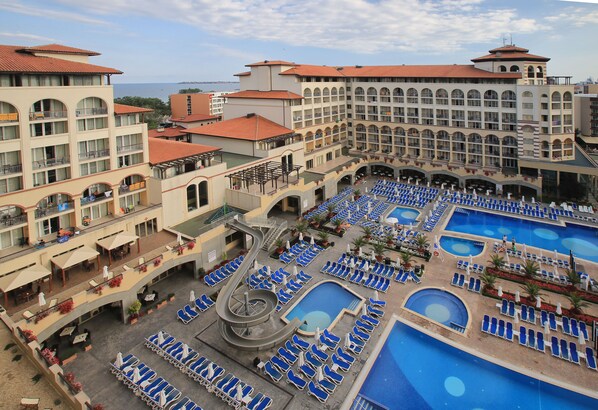 A hotel with multiple swimming pools, a central water slide, and numerous lounge chairs arranged around the pools. - Meliá Sunny Beach Resort (Sunny Beach)
